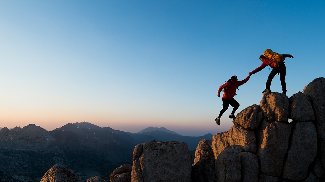 Two people climb a mountain toegether and showing tremendous willpower